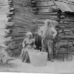 Former Slaves Standing in Front of their Cabin